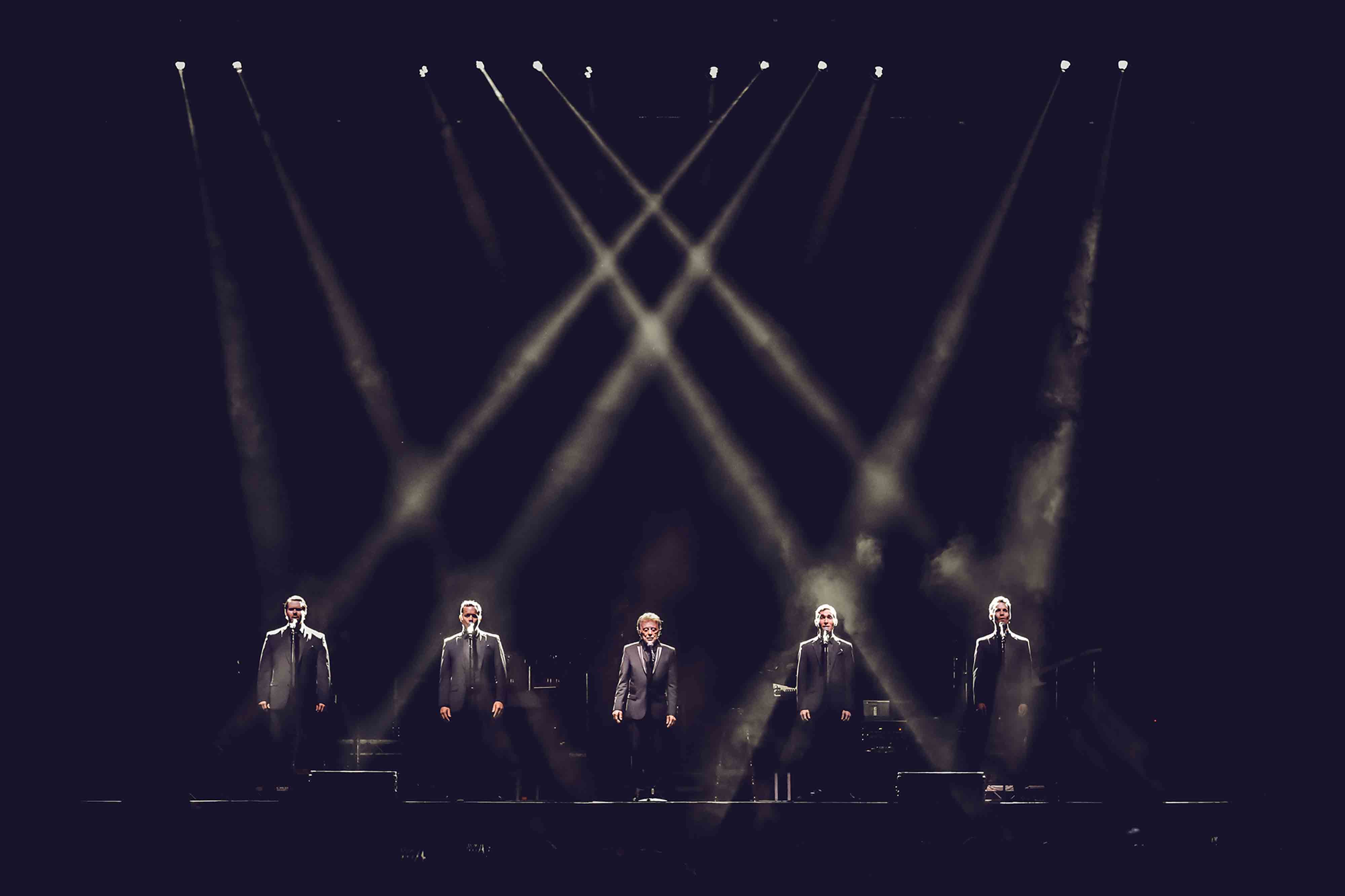 Frankie Valli with four other singers onstage in dramatic lighting